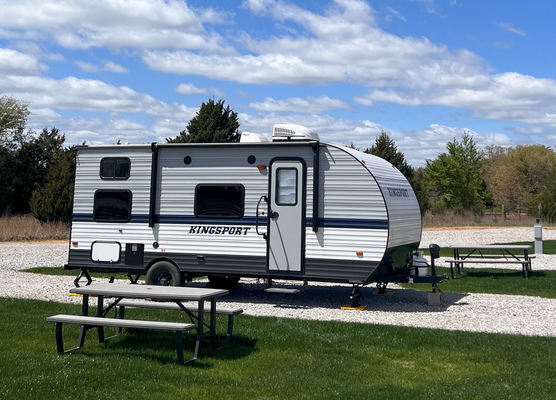 Travel trailer parked at spacious pull-thru RV site with picnic table at Roadrunner Ranch near WinStar